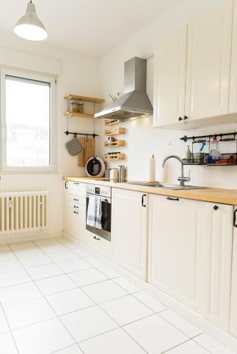 een keuken met witte kasten en een witte tegelvloer bij - NEU - Große & gemütliche 3 Zimmer Wohnung in Neulsenburg