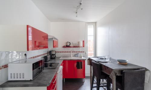 une cuisine avec des placards rouges et blancs et une table dans l'établissement Studio Le Cosy - 100m Plage d'Etretat - 4 personnes, à Étretat