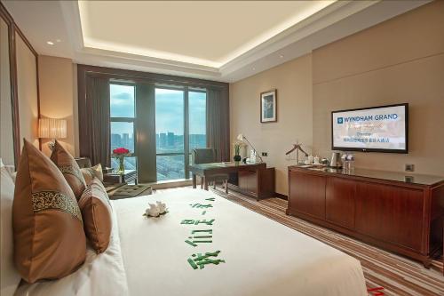 a hotel room with a bed and a desk and a television at Wyndham Grand Plaza Royale Chenzhou in Chenzhou