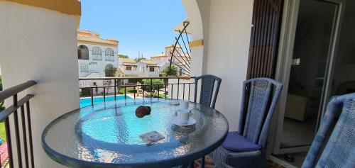einen Glastisch auf einem Balkon mit Pool in der Unterkunft Дуплекс " Torre Gala" Playa Flamenca in Playa Flamenca