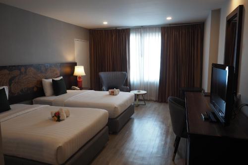 a hotel room with two beds and a flat screen tv at Empress Pattaya Hotel in Pattaya