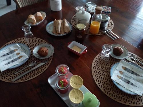 een houten tafel met borden ontbijtproducten erop bij Entre terre et mer in Ploemeur