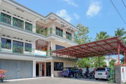 a large white house with a balcony and motorcycles at RedDoorz At Telaga Mulya Hotel Wates in Yogyakarta
