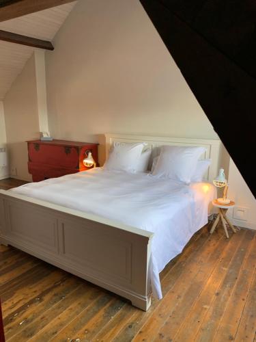 a bedroom with a large white bed with a wooden floor at Hygge Vakantiewoning in Ostend