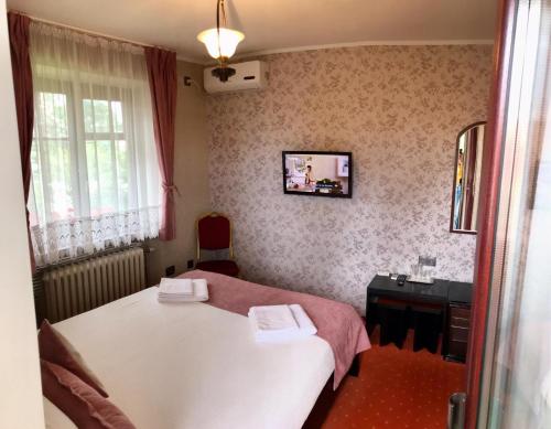 a small bedroom with a white bed and a window at Pension Hotel Fast in Rădăuţi
