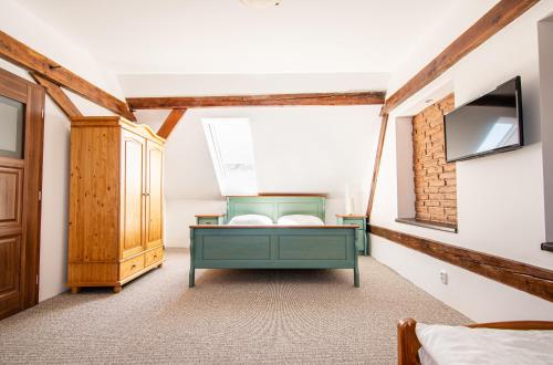 a bedroom with a green bed and a tv at Penzion Zlaté Slunce in Chocenice