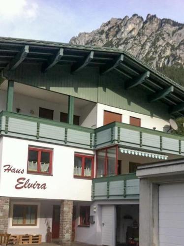 ein grün-weißes Gebäude mit einem Berg im Hintergrund in der Unterkunft Haus Elvira in Klösterle am Arlberg
