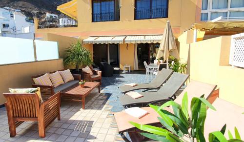 a patio with chairs and tables on a building at HD Mogan Beach Apartment in Puerto de Mogán