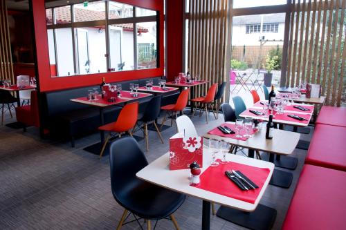 a restaurant with tables and chairs and red walls at ibis Bayonne Centre in Bayonne