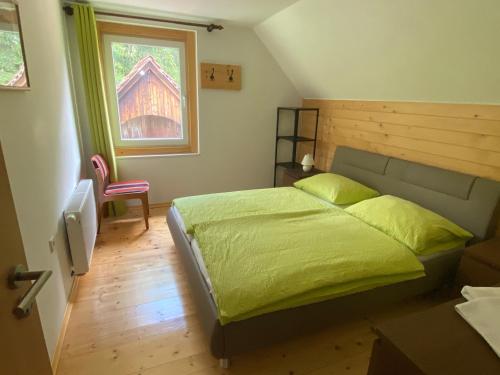 Un dormitorio con una cama verde y una ventana en Sobe v Gozdu, en Gozd Martuljek