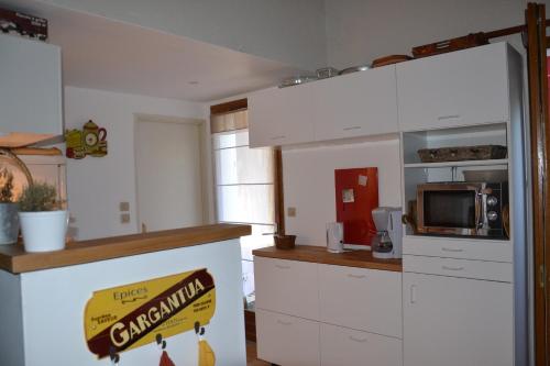 une cuisine avec des armoires blanches et un panneau guépard sur le comptoir dans l'établissement Le patio de Torreilles-Plage, à Torreilles