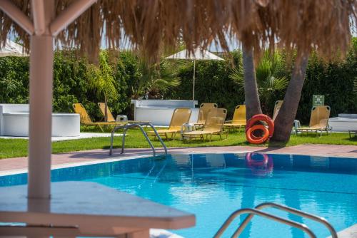 a swimming pool with chairs and an umbrella at I Candy Malia by Estia in Malia