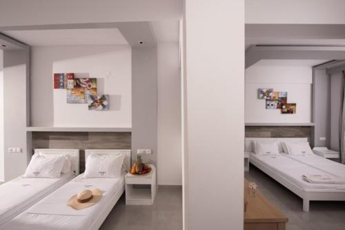 two beds in a room with white walls at I Candy Malia by Estia in Malia