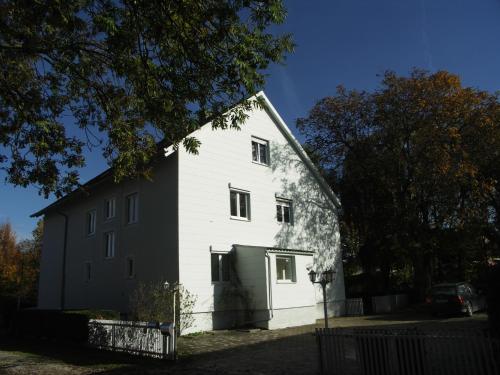 eine große weiße Scheune mit grüner Garage in der Unterkunft Haus am Bach - gemütliche Frühstückspension in Allershausen