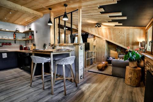 a kitchen with a bar with stools and a living room at Studio Lessy - Centre village - AravisTour in Saint-Jean-de-Sixt