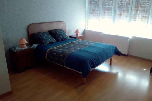 1 dormitorio con 1 cama con manta azul y ventana en Maison au coeur du village, en Dorlisheim
