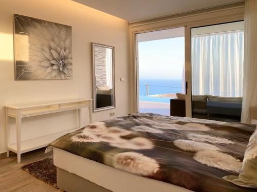 a bedroom with a bed with a view of the ocean at Holiday Apartment Sunset Ocean in Ribeira Brava