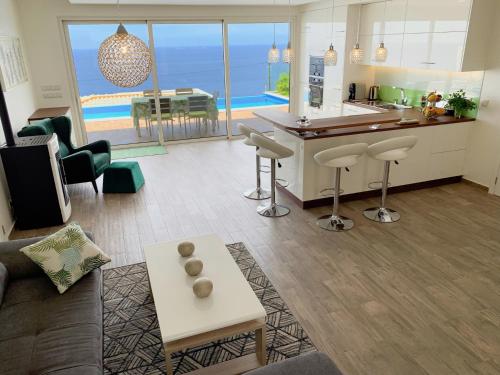 a living room with a couch and a kitchen with a view at Holiday Apartment Sunset Ocean in Ribeira Brava