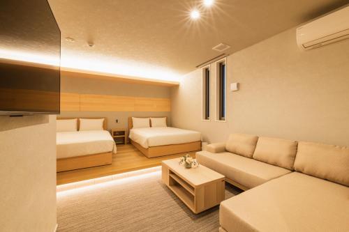 uma sala de estar com duas camas e um sofá em GRAND BASE Hakata Station em Fukuoka