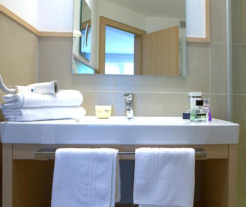 bagno con lavandino, asciugamani e specchio di Hotel Seeber a Racines