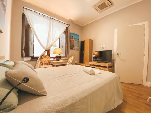 a bedroom with a large white bed and a window at Apodaca Rooms in Cádiz