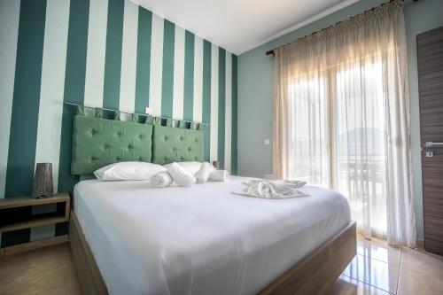 a bedroom with a large white bed with a striped wall at ONITES Elegant Suites in Skala Potamias