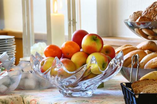 a glass bowl of apples and bread on a table at Hotel Kaiserpfalz in Paderborn