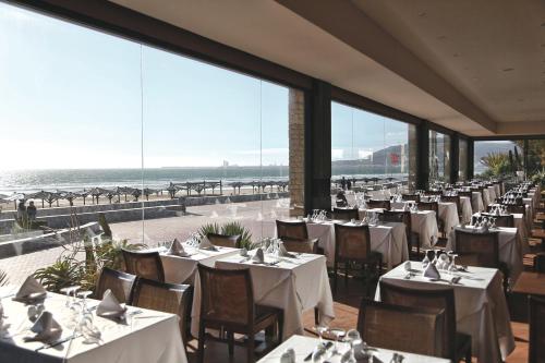 a restaurant with tables and chairs with a view of the ocean at Hotel Riu Tikida Beach - Adults Only - All inclusive in Agadir