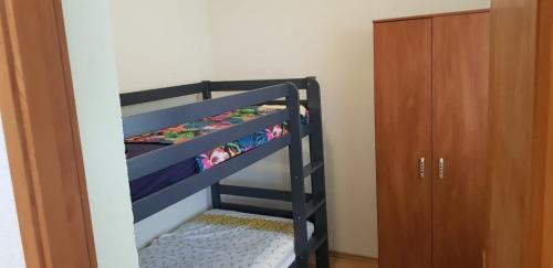 ein schwarzes Etagenbett in einem Zimmer mit einem Schrank in der Unterkunft Srećko Apartman in Rogoznica