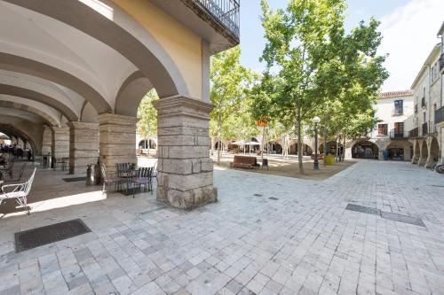 an arcade with chairs and trees in a courtyard at Lovely & Cozy apartment in the heart of Banyoles in Banyoles