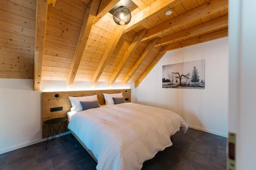 - une chambre avec un grand lit dans une pièce dotée de plafonds en bois dans l'établissement Moderne 3 Zi.-FeWo BlackForestArt Nähe Freiburg, à Simonswald