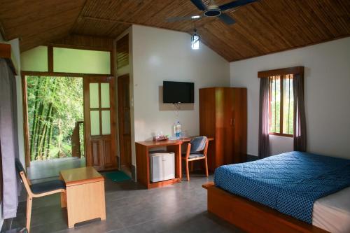 a bedroom with a bed and a desk and a television at Balishira Resort Ltd. in Sreemangal