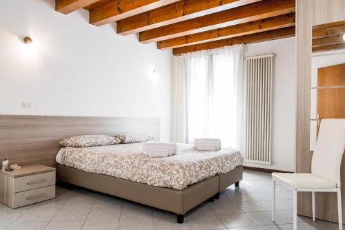 a white bedroom with a bed and a white chair at INTERO APPARTAMENTO nel cuore di VICENZA in Vicenza