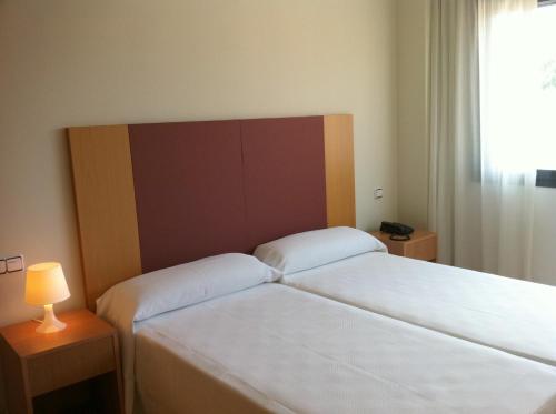 ラス・ロサス・デ・マドリードにあるHotel-Apartamentos Tartesosのベッド2台と窓が備わるホテルルームです。