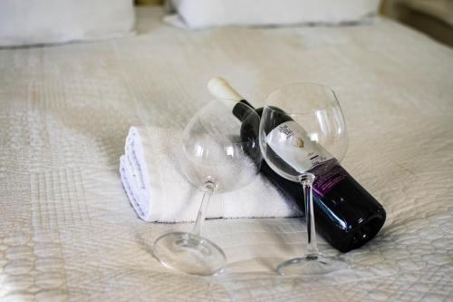 two wine glasses sitting on top of a bed at Shkutai Hottub Arava in Ẕofar