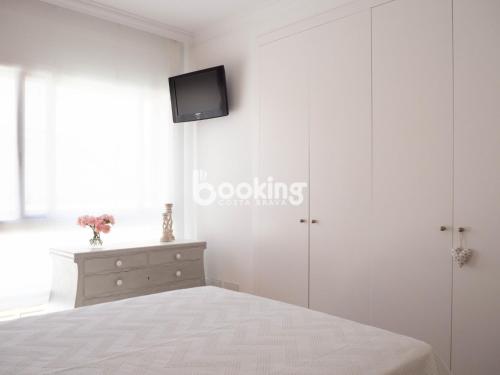 1 dormitorio con 1 cama y TV en la pared en Indústria Apartament per 3 persones a 2 minuts de la platja amb Aire acondicionat i plaça d'aparcament, en Sant Feliu de Guíxols