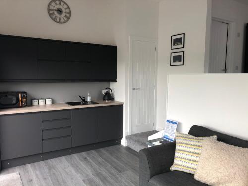 a kitchen with a couch and a clock on the wall at The apartment at Glendaruel in Portree