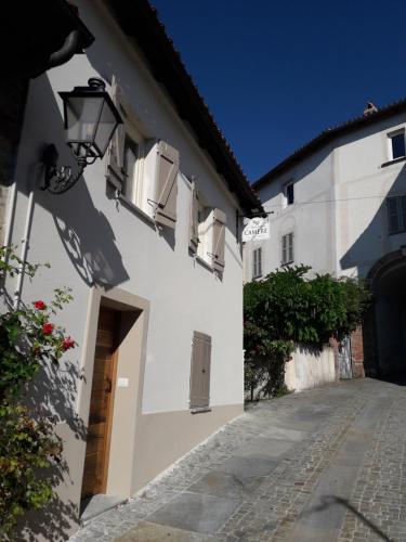 a white building with a door and a street at Al biancospino- Camere- Ristorante in Bossolasco