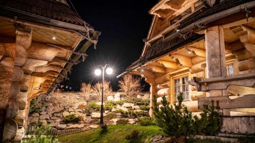 a wooden house with a street light in front of it at Osada Kościelisko - Tatry na Wyciągnięcie Ręki in Kościelisko