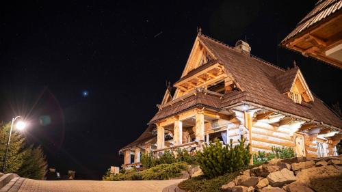 a large wooden house with a roof at night at Osada Kościelisko - Tatry na Wyciągnięcie Ręki in Kościelisko