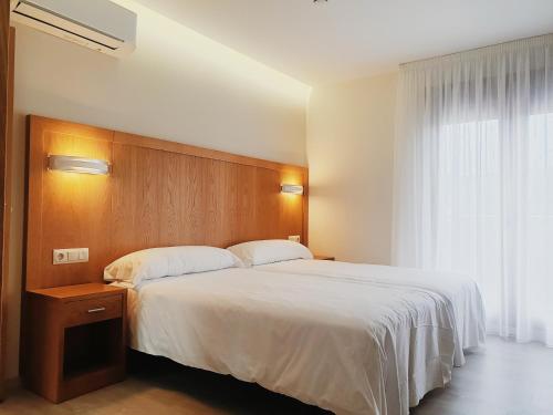 a bedroom with a large white bed and a window at Hotel Campomar 3*** Superior in A Lanzada