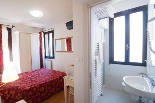 uma pequena casa de banho com uma cama e um lavatório. em Albergo ai Tolentini em Veneza