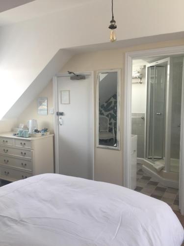 a bedroom with a white bed and a dresser at The Alendale Guesthouse in Weymouth