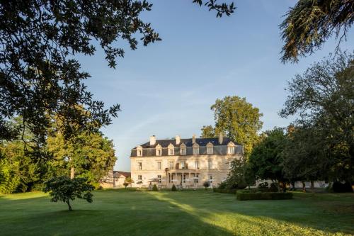 a large house on a green field with trees at La Maison d'Estournel in Saint-Estèphe