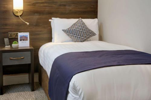 a bedroom with a bed with a wooden head board at Trafford Hall Hotel Manchester, Trademark Collection by Wyndham in Manchester