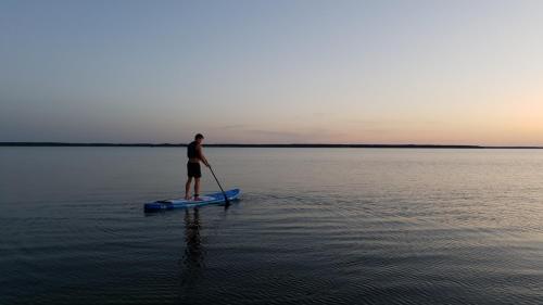 a man standing on a paddle board in the water at Marise Holiday Home in Õeste