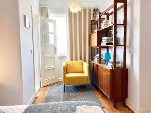 a bedroom with a yellow chair and a book shelf at Home Out Central Roma Apartment in Lisbon