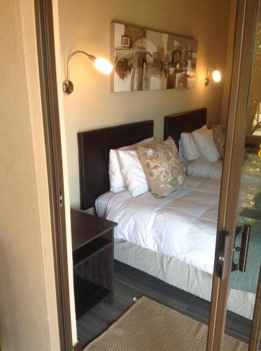 a bedroom with a bed with white sheets and a mirror at Jock of the Bushveld in Barberton