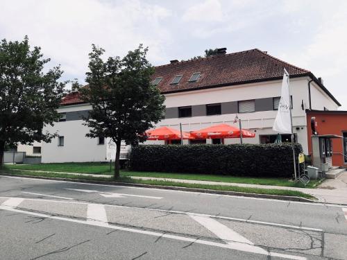 a white building with red umbrellas on a street at Pension Auer in Liebenfels