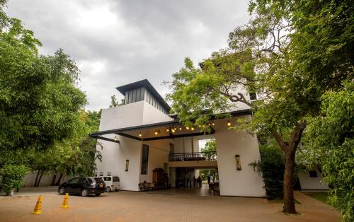 a white building with a car parked in a parking lot at Grand Tamarind Lake in Kataragama